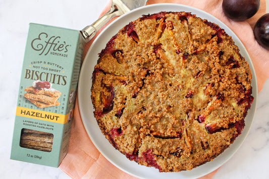 A plum tart with an Effie's Hazelnut crumb topping, sitting next to a box of Hazelnut Biscuits