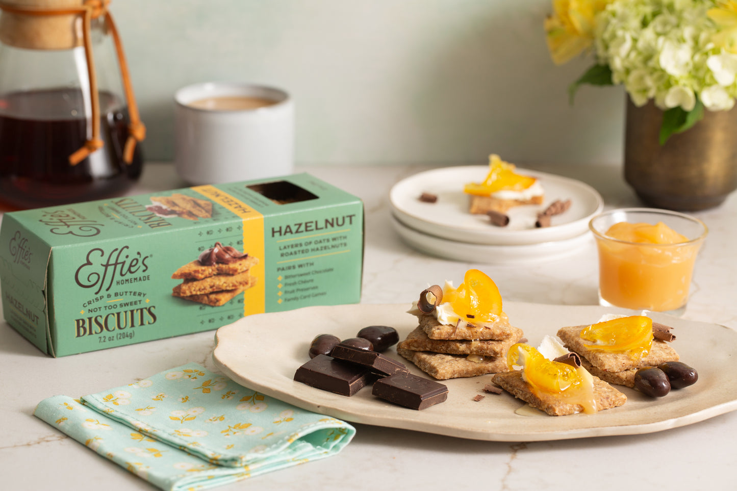 Effie's Hazelnut Biscuits served with dark chocolate pieces, a dollop of whipped cream, and marmalade, showcasing their rich, nutty flavor and versatility for both dessert and snack pairings.