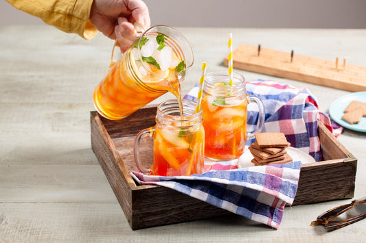 Outdoor scene with tray of glasses and someone pouring from a pitcher of iced tea, alongside a snack plate of Pecan Biscuits